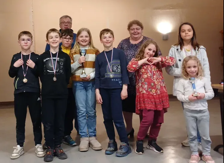 Un groupe d'enfants souriants, médailles autour du cou et coupes en main, lors d'une remise de prix