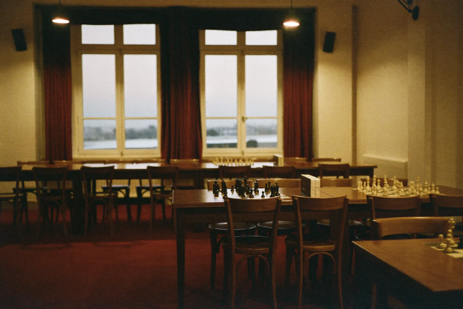 La salle du club un soir de séance, les échiquiers dressés sous les lampes