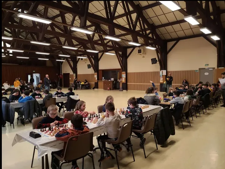 Une grande salle de tournoi remplie de jeunes joueurs concentrés sur leurs échiquiers